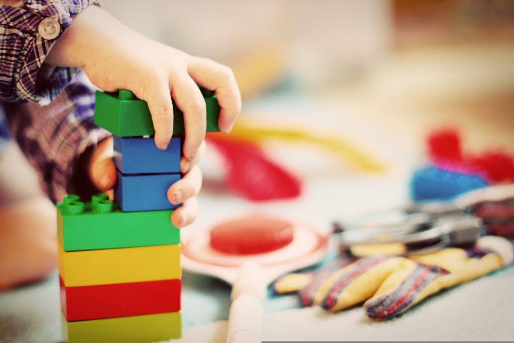 Kind spielt in der Kita mit Duplo Bausteinen