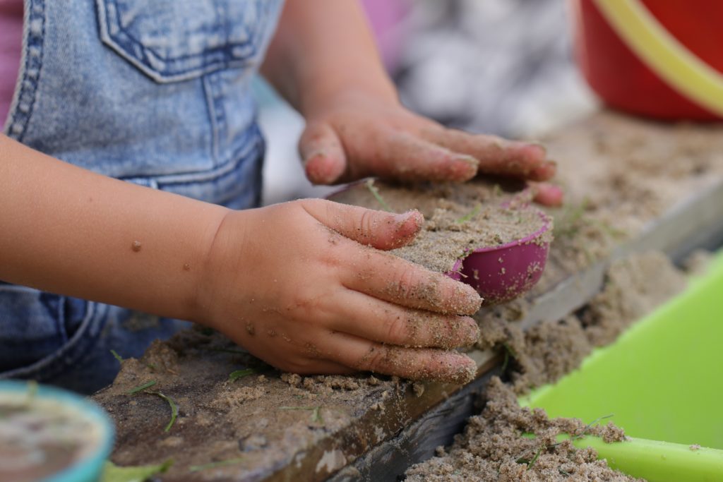 Ein Kind spielt in der Kita im Sand mit Förmchen